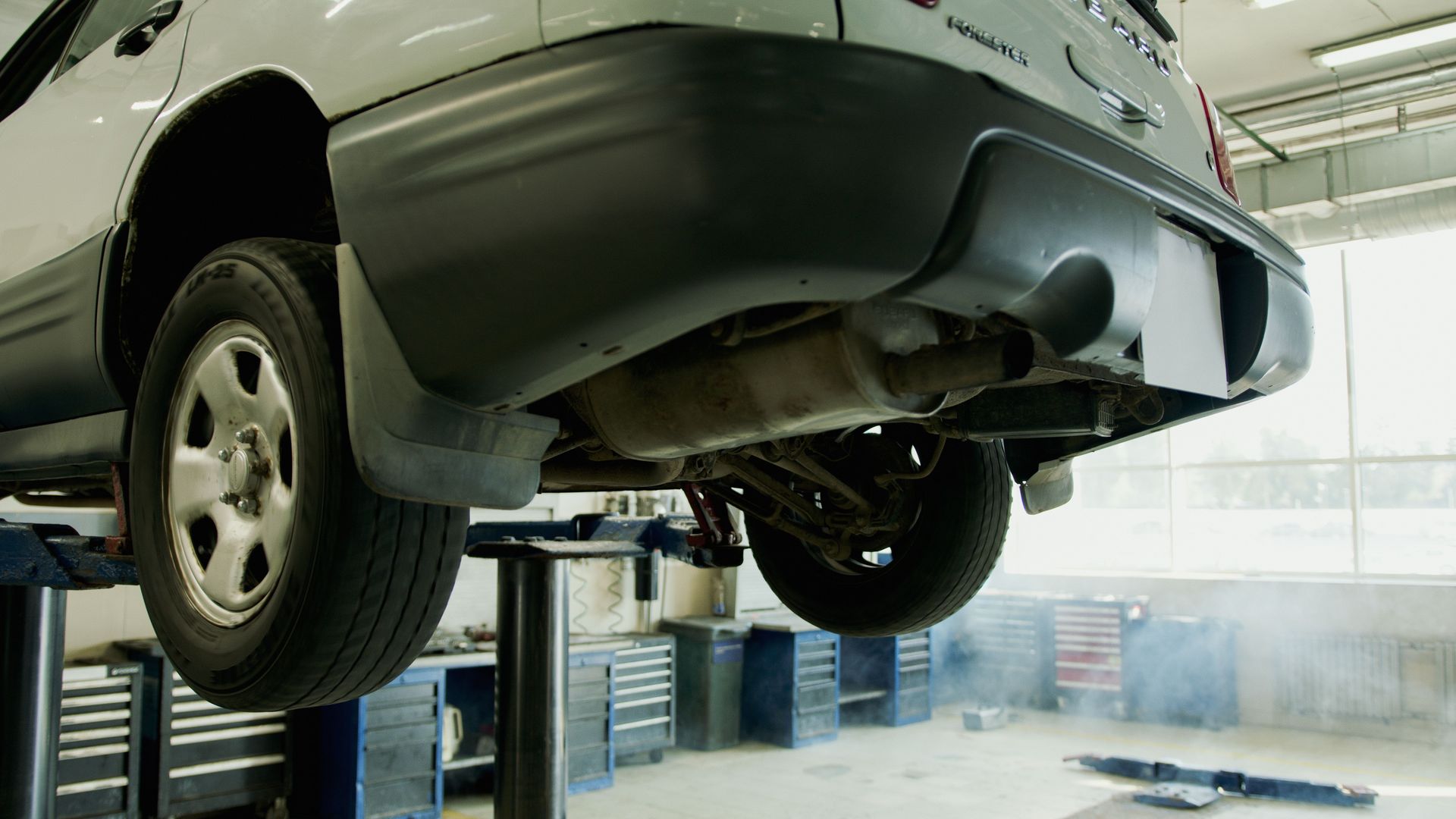 A vehicle elevated on a lift in an auto repair shop, ready for service.